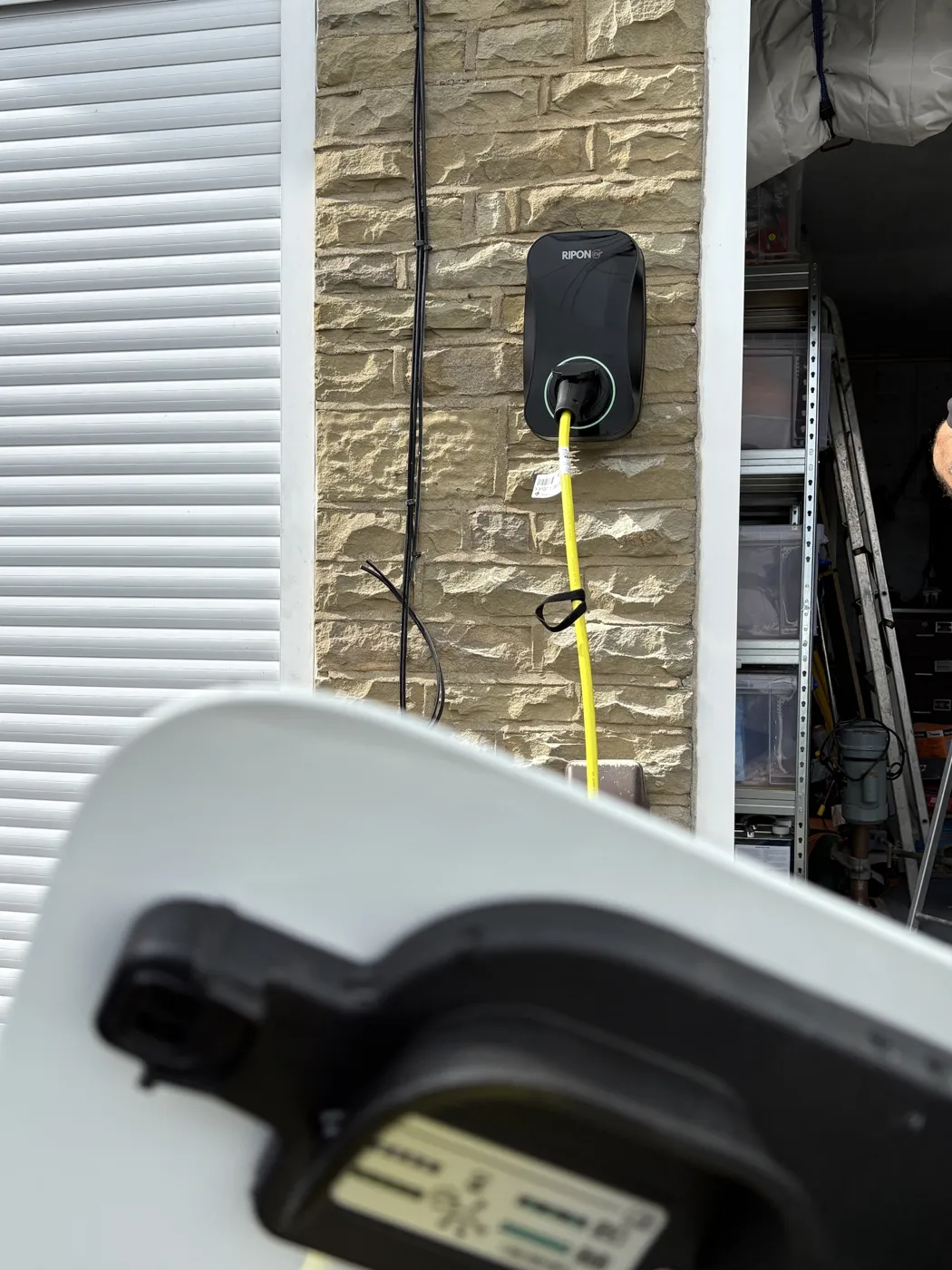 RiponEV charger on a stone garage pier with a car plugged in