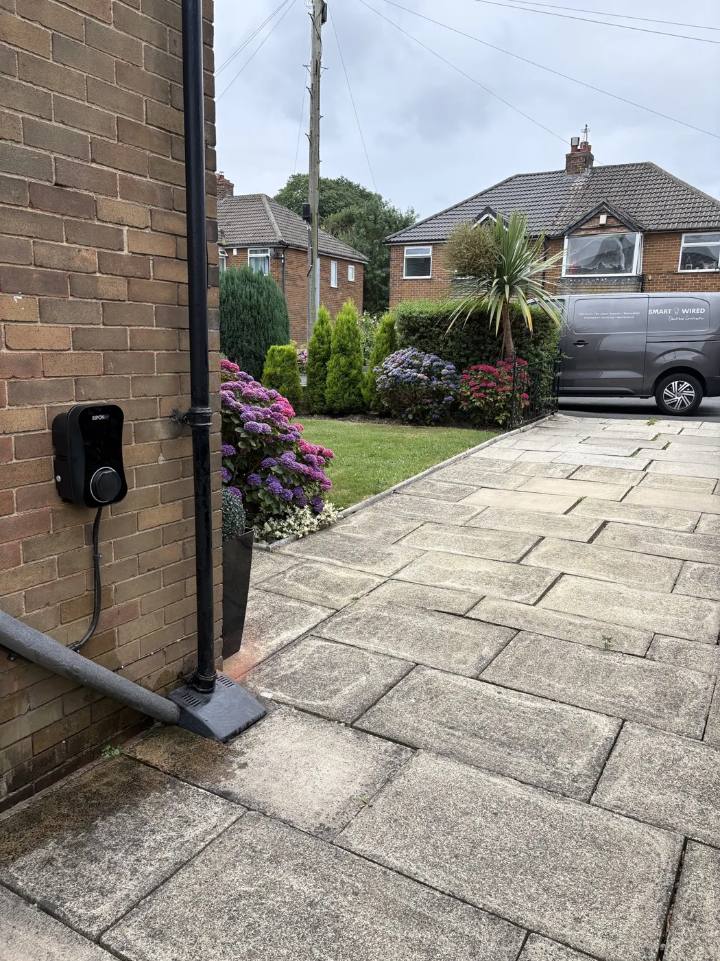 Untethered RiponEV charger fixed to a stone wall beside the drive at a Bradford home