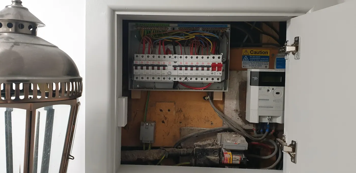 Older consumer unit in a hallway cupboard with the cover off