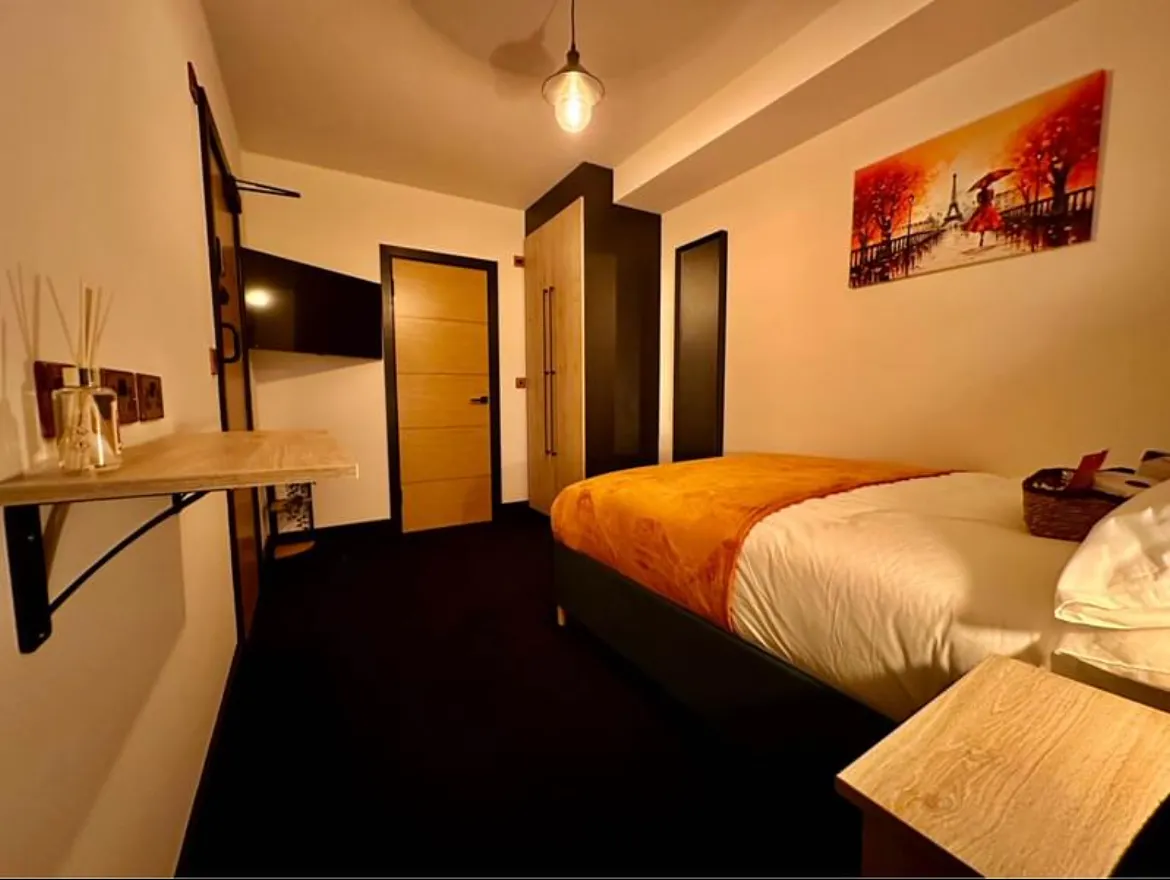 Finished bedroom with pendant light, sockets and wall-mounted TV