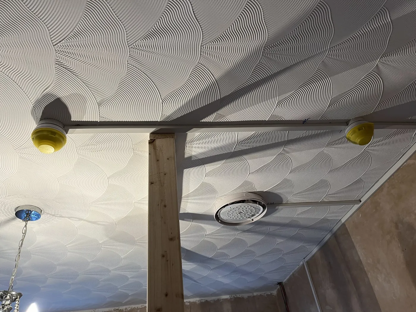 Interlinked fire detectors with protective covers and an emergency light fitting on the ceiling
