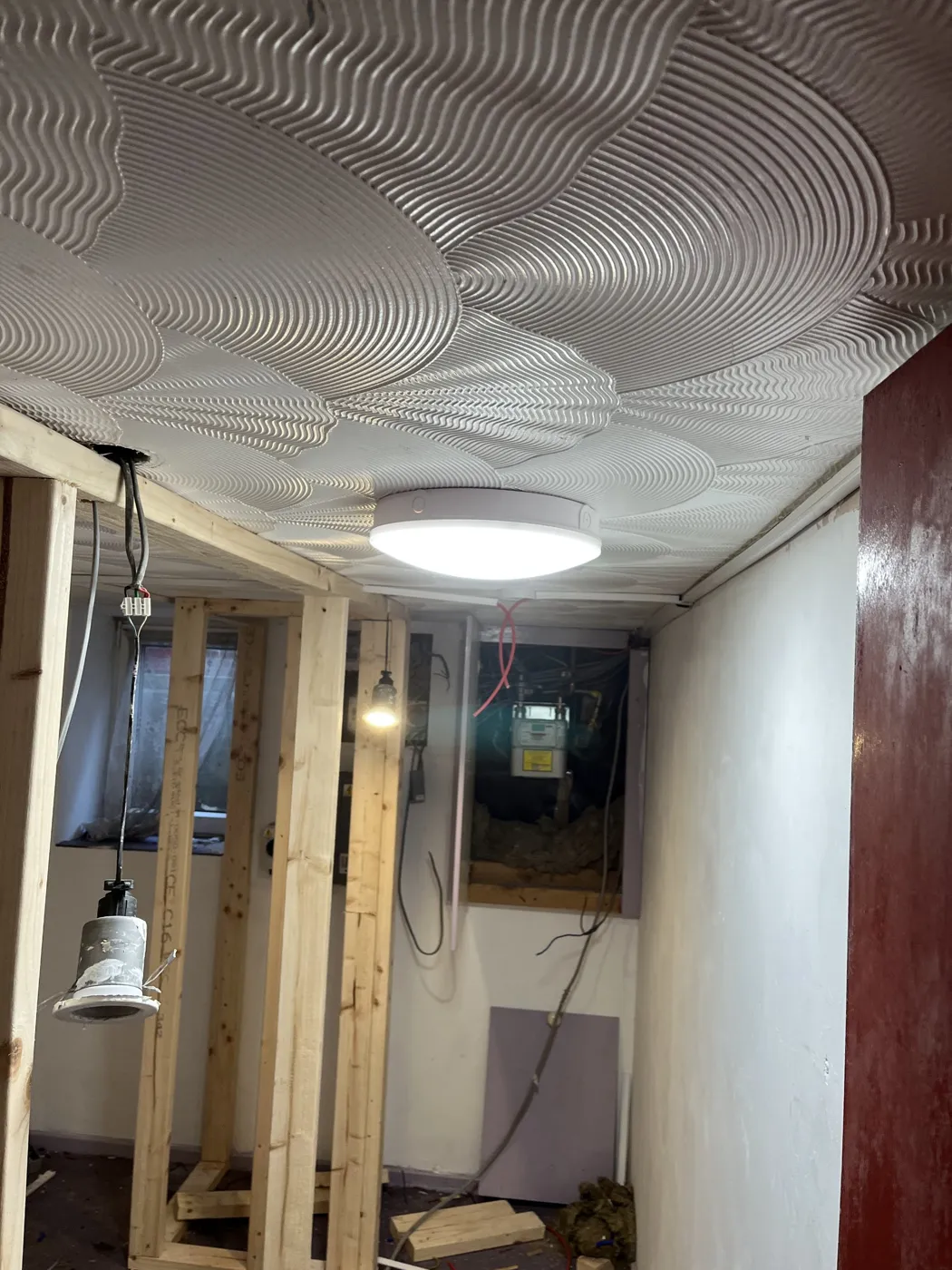 New ceiling light fitted in a lobby during a conversion, with downlight ready
