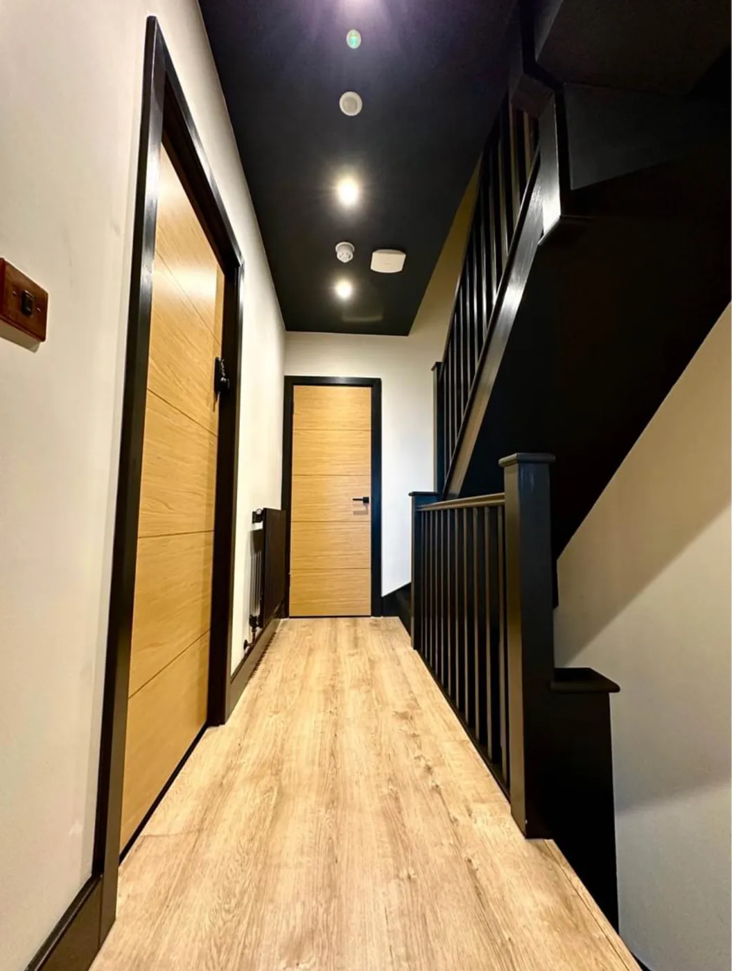 Finished landing with LED downlights, smoke detector and emergency light on a dark ceiling