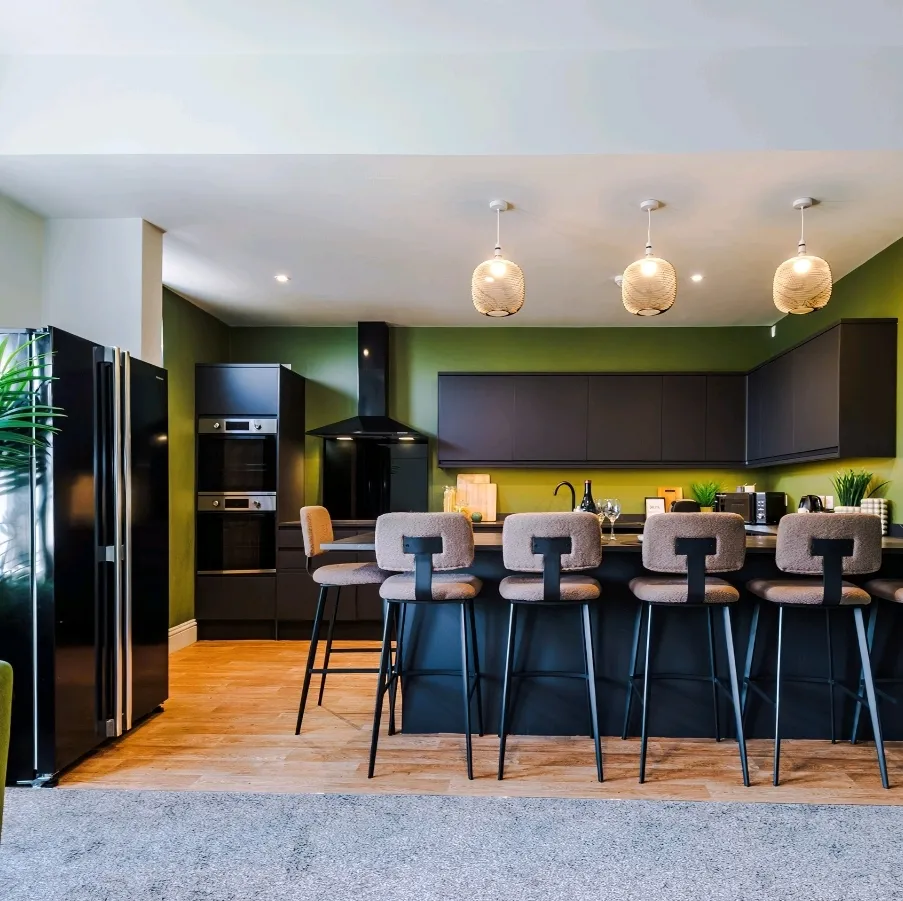 Finished shared kitchen with three pendant lights over a breakfast bar and LED downlights