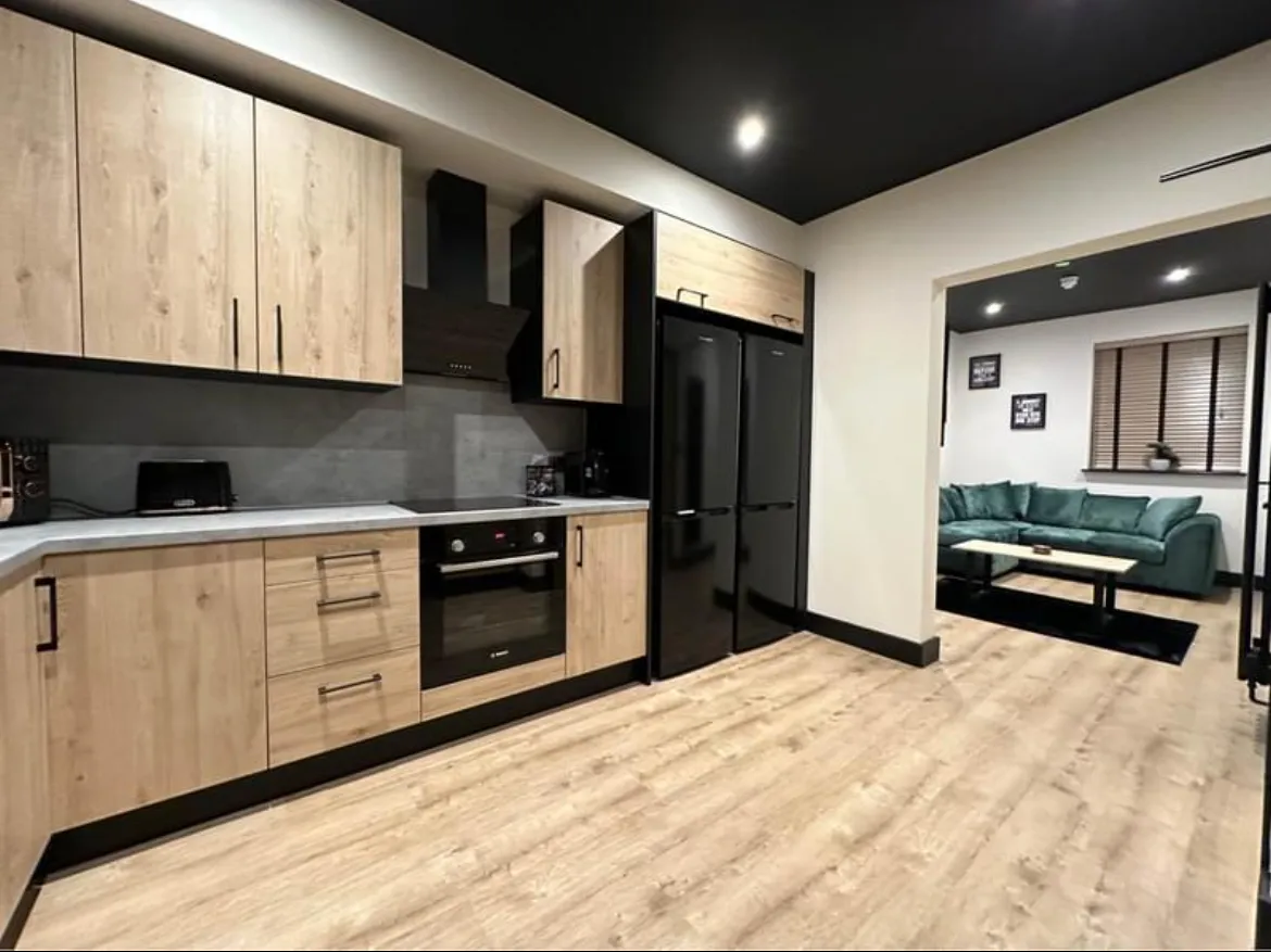 Finished kitchen with downlights, cooker circuit and appliances, opening into a lounge