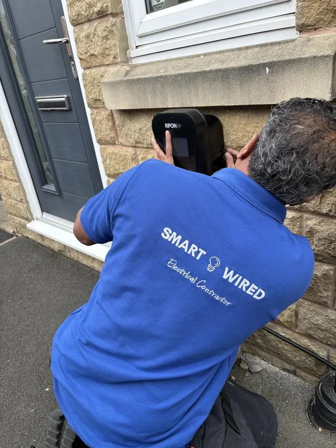 SmartWired electrician fitting an EV charger to a house wall