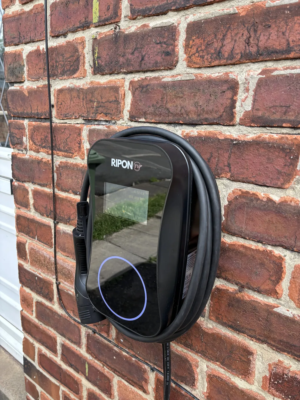Side view of a tethered RiponEV display charger on old red brick