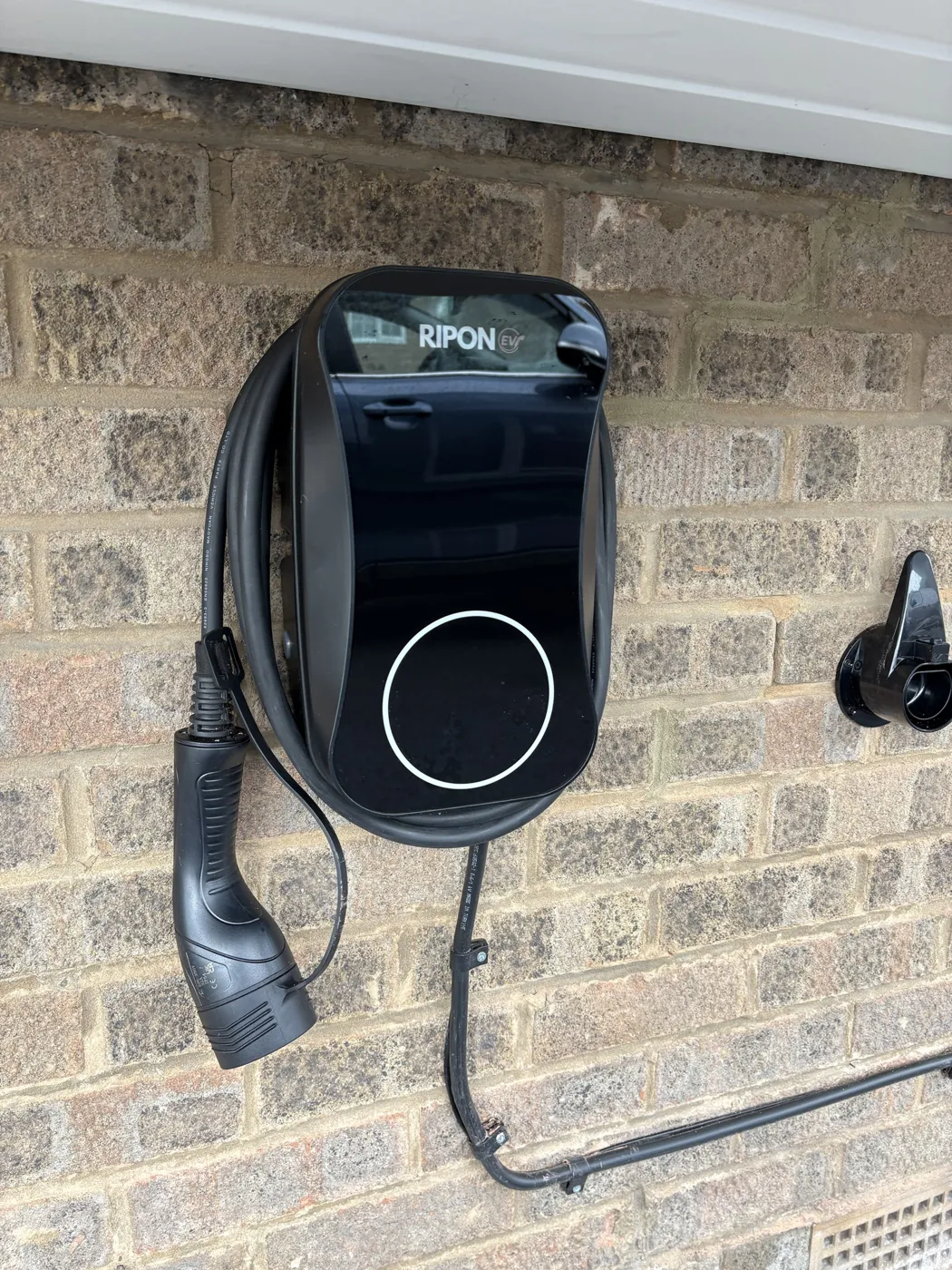 Tethered RiponEV charger with cable wrapped and a separate holster on buff brick