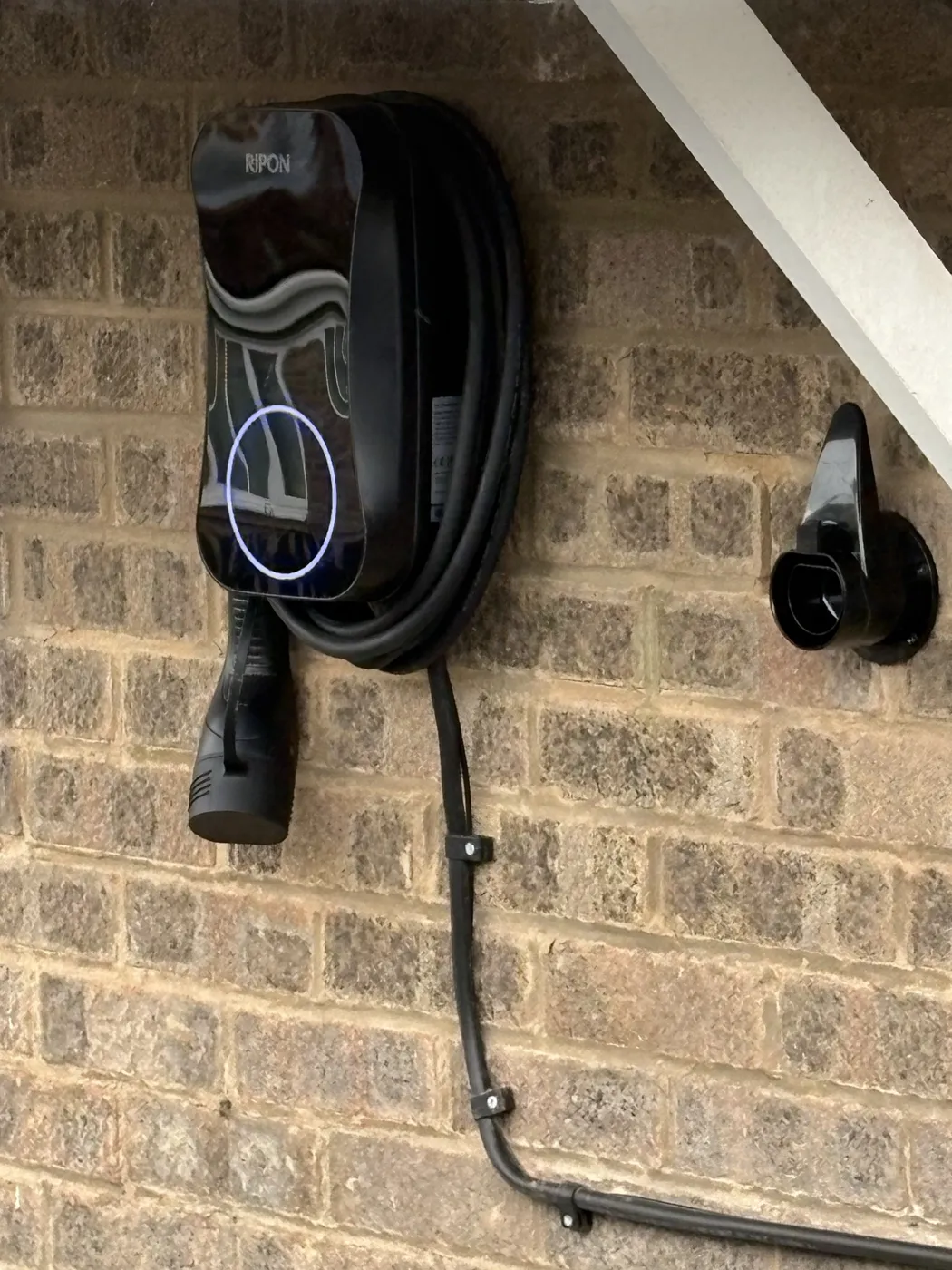 Tethered RiponEV charger under the eaves with the cable clipped neatly down the wall