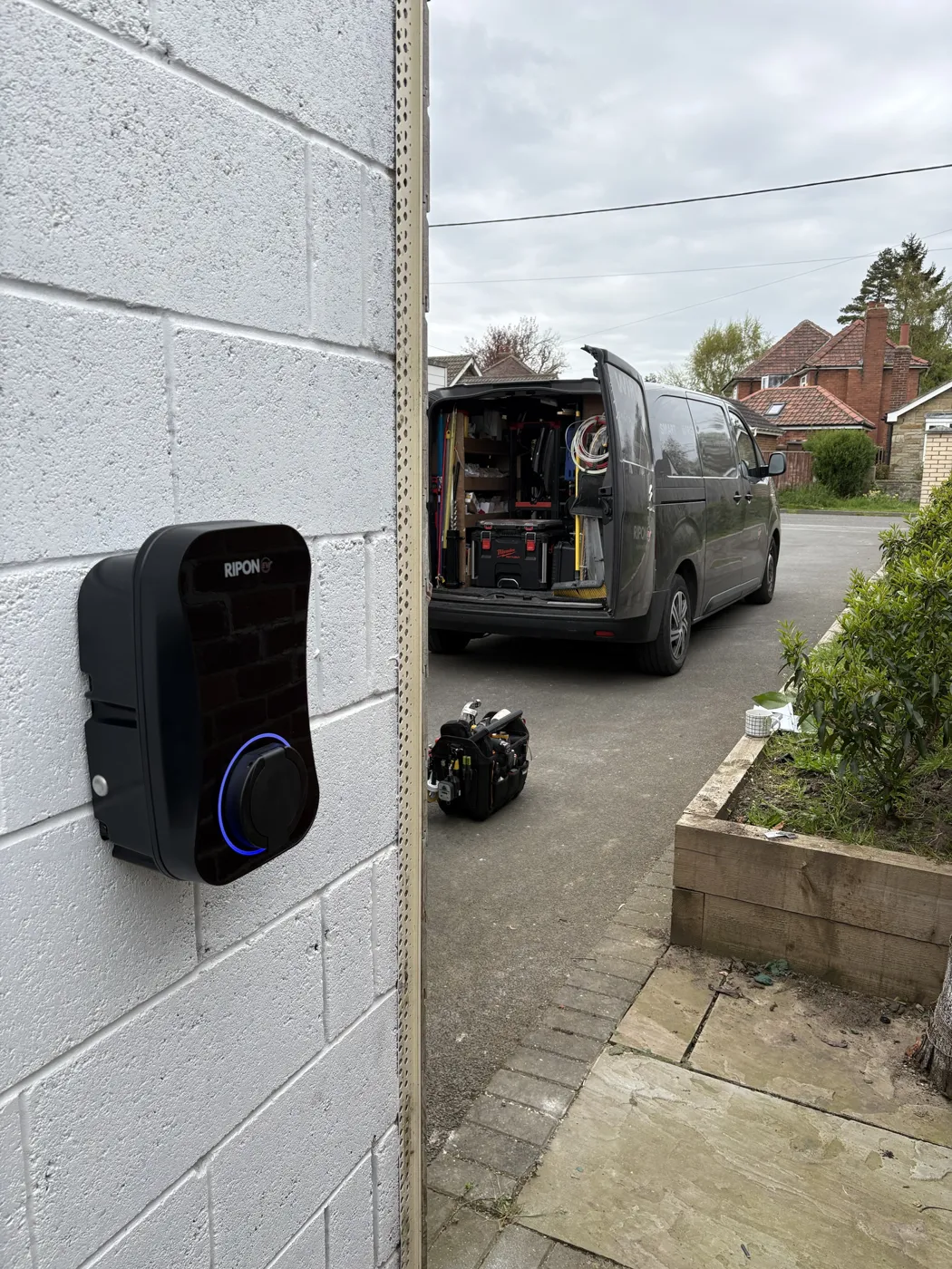RiponEV charger on a painted block wall with the RiponEV van on the drive