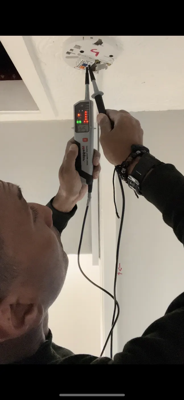 Electrician testing a ceiling rose with a two-pole voltage tester