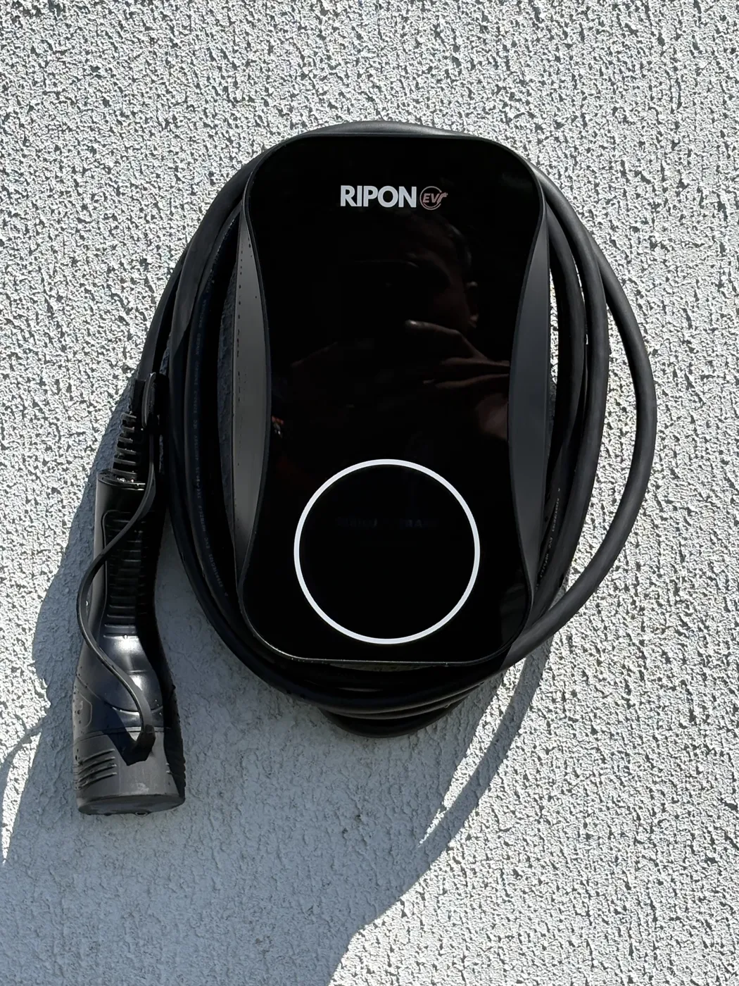 Tethered RiponEV charger with cable wrapped on a white rendered wall at a Halifax home
