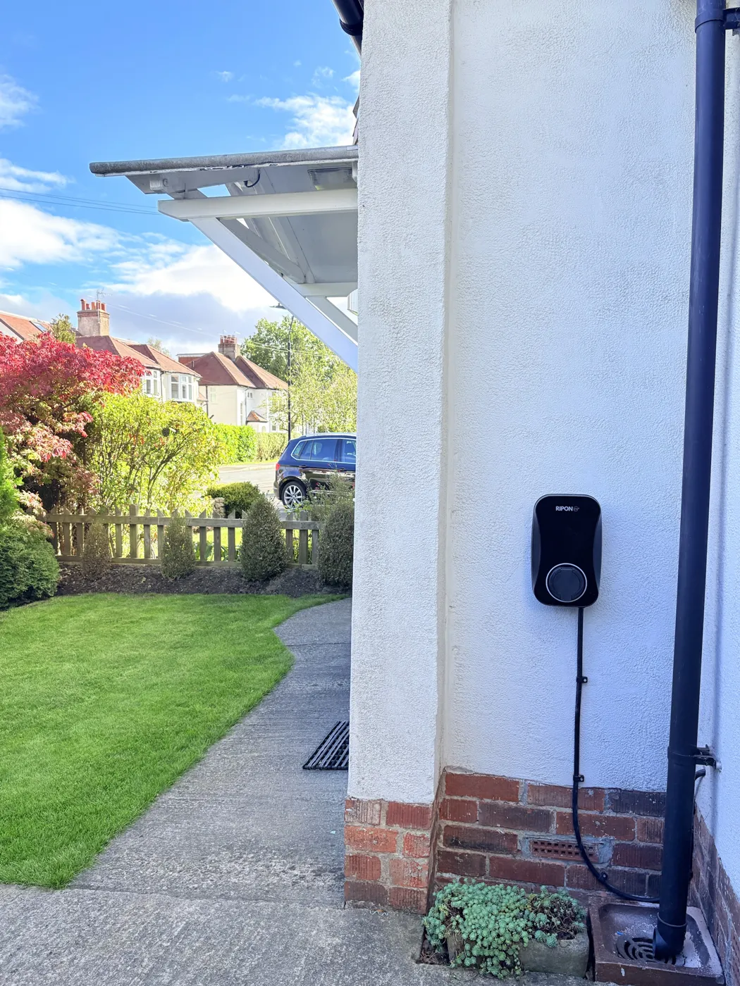 RiponEV charger on the side of a white rendered house in Harrogate beside the garden path