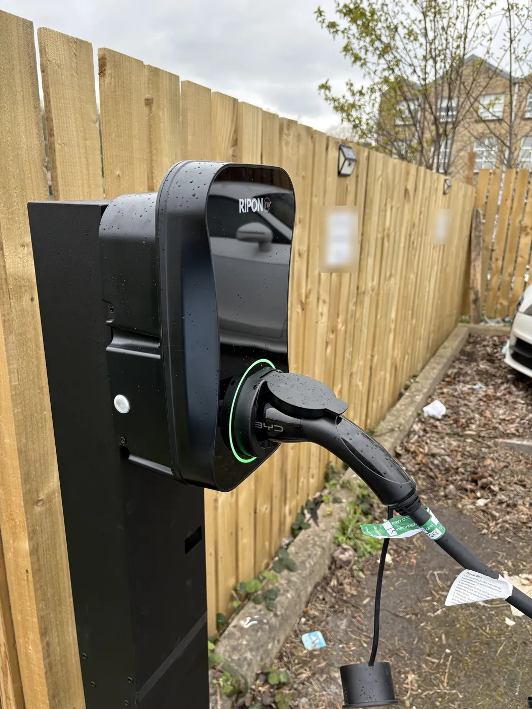 Close-up of a post-mounted RiponEV charger charging in the rain