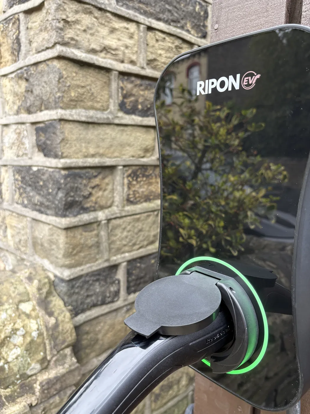 Close-up of a RiponEV charger plugged in against Yorkshire stone
