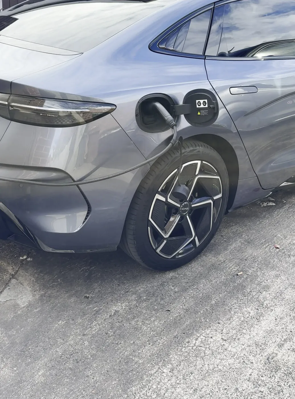 Grey electric saloon plugged in and charging on a Hull driveway