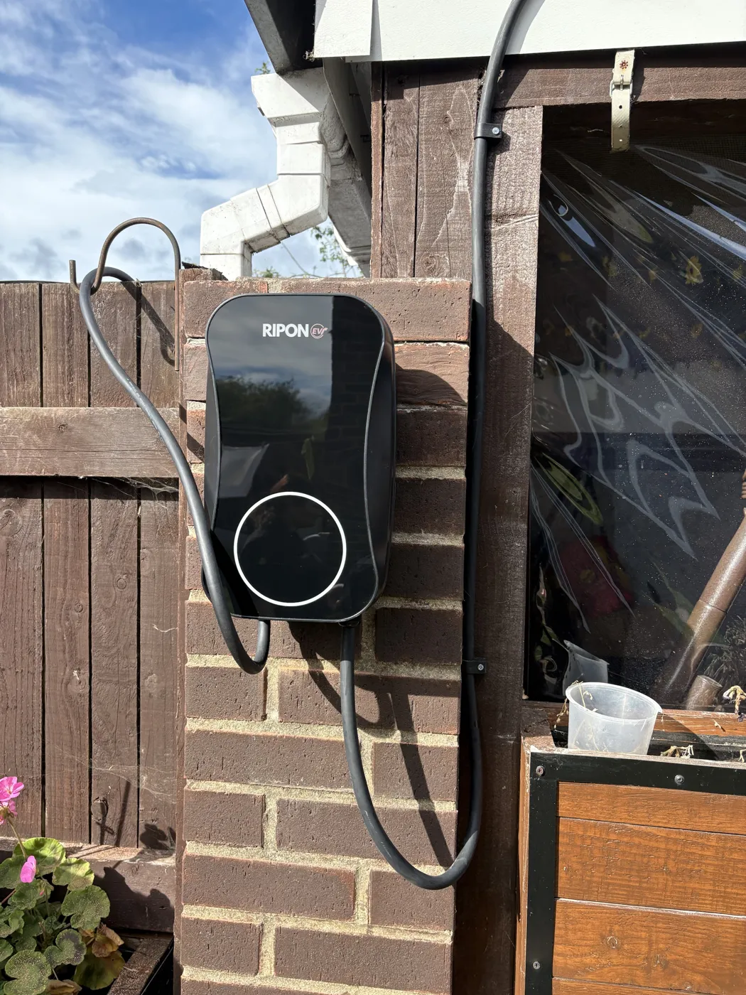 Tethered RiponEV charger on a brick pier between a garden fence and a shed at a home in Hull