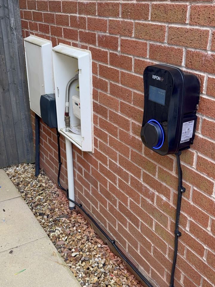 Armoured cable clipped neatly along a house wall to an EV charger