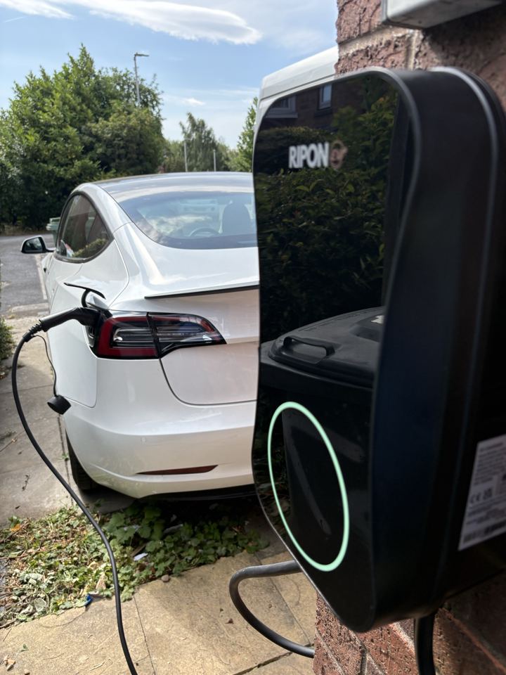EV charger charging a white Tesla on a driveway