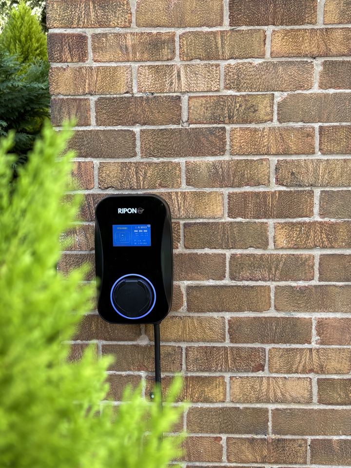 RiponEV Premium charger with LCD screen on a brick wall
