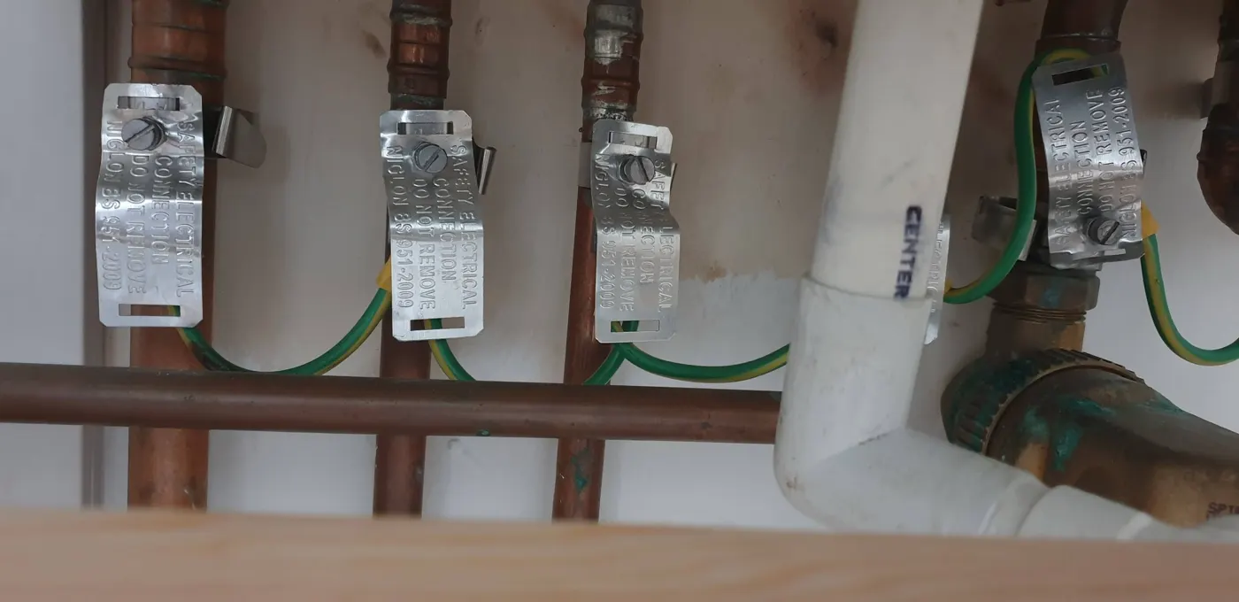 Main protective bonding clamps fitted to gas and water pipes