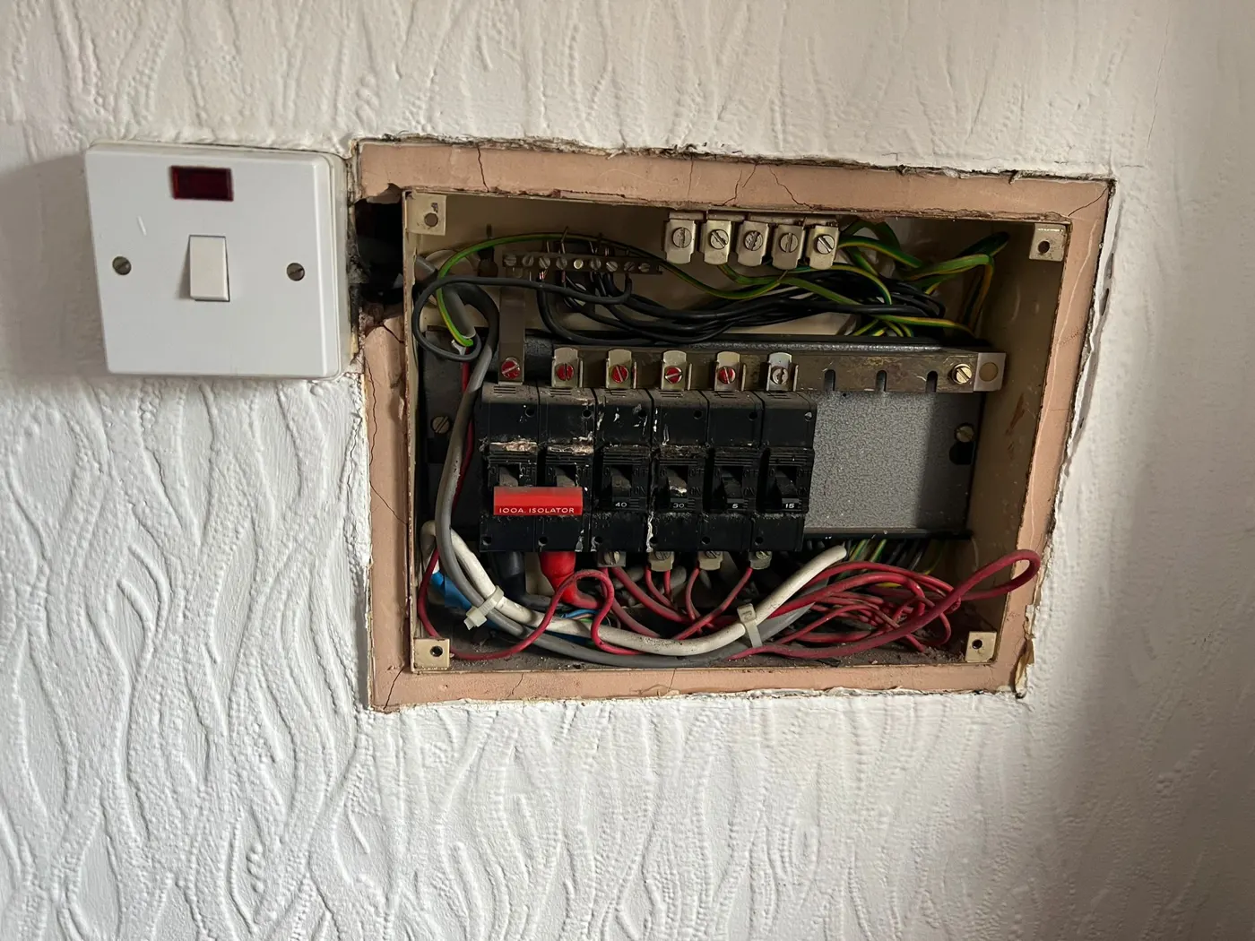 Old recessed board with exposed wiring and cracked surround