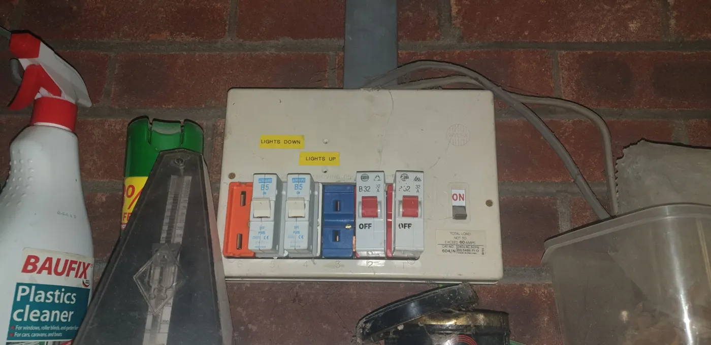 Older Wylex board with plug-in MCBs and a rewireable fuse in a garage