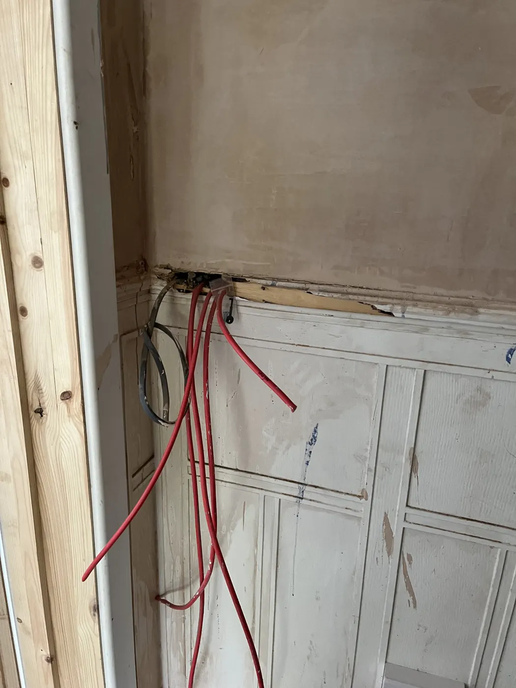 Fire-resistant red cable run behind old panelling during a rewire