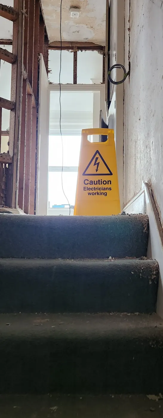 Landing during a rewire with floors protected and a caution sign