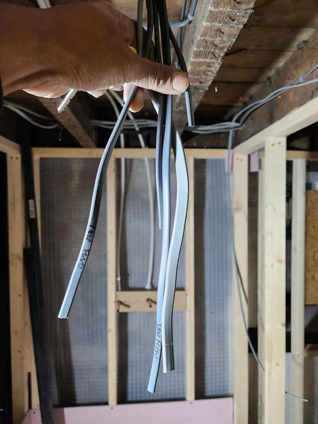 Electrician holding new cables labelled by circuit