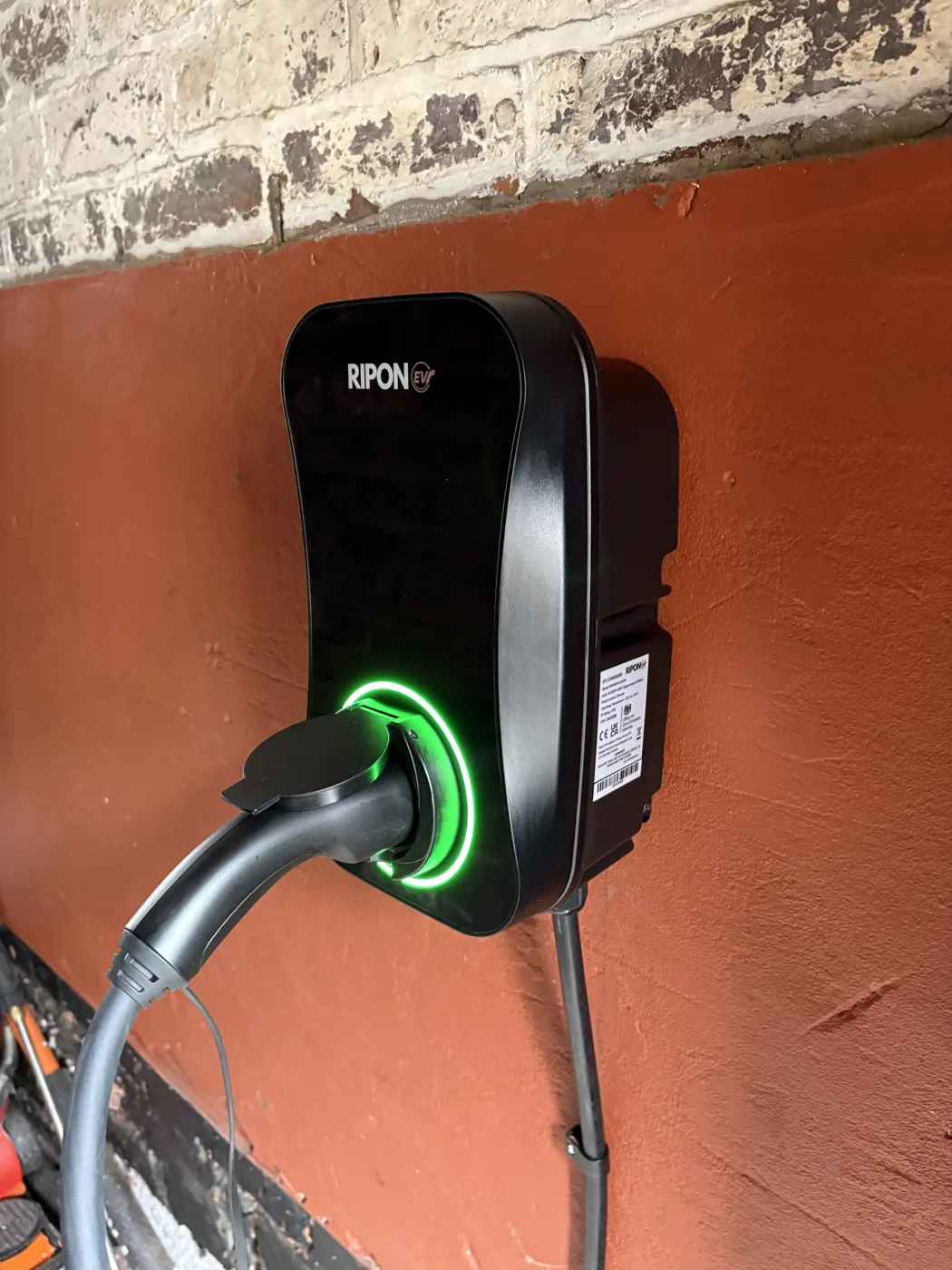 RiponEV charger inside a garage, plugged in with the green ring lit