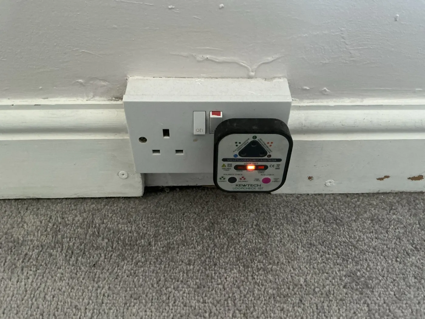Plug-in socket tester showing a loop check warning