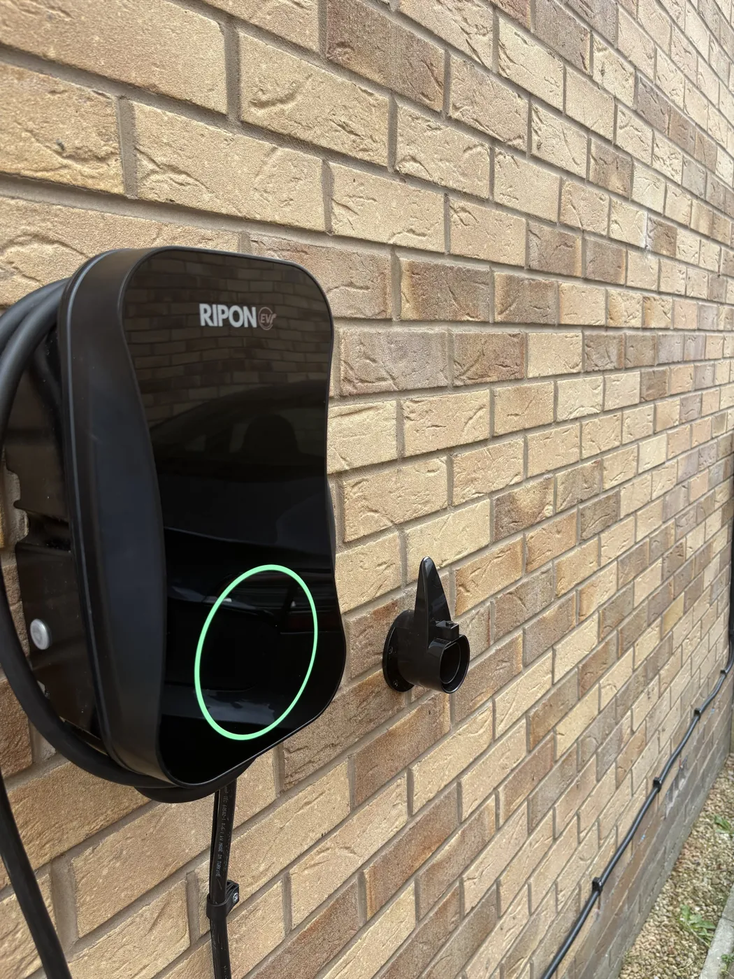 Close-up of a tethered RiponEV charger with a wall-mounted connector holster