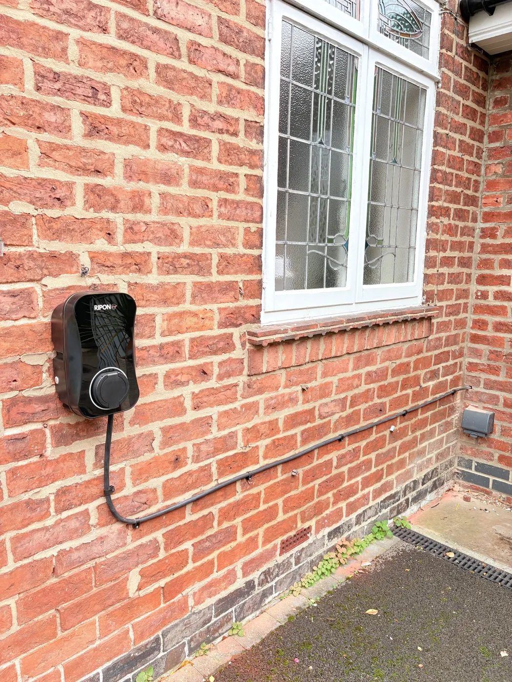 RiponEV Pro untethered charger on a red brick house in York, cable clipped neatly along the wall